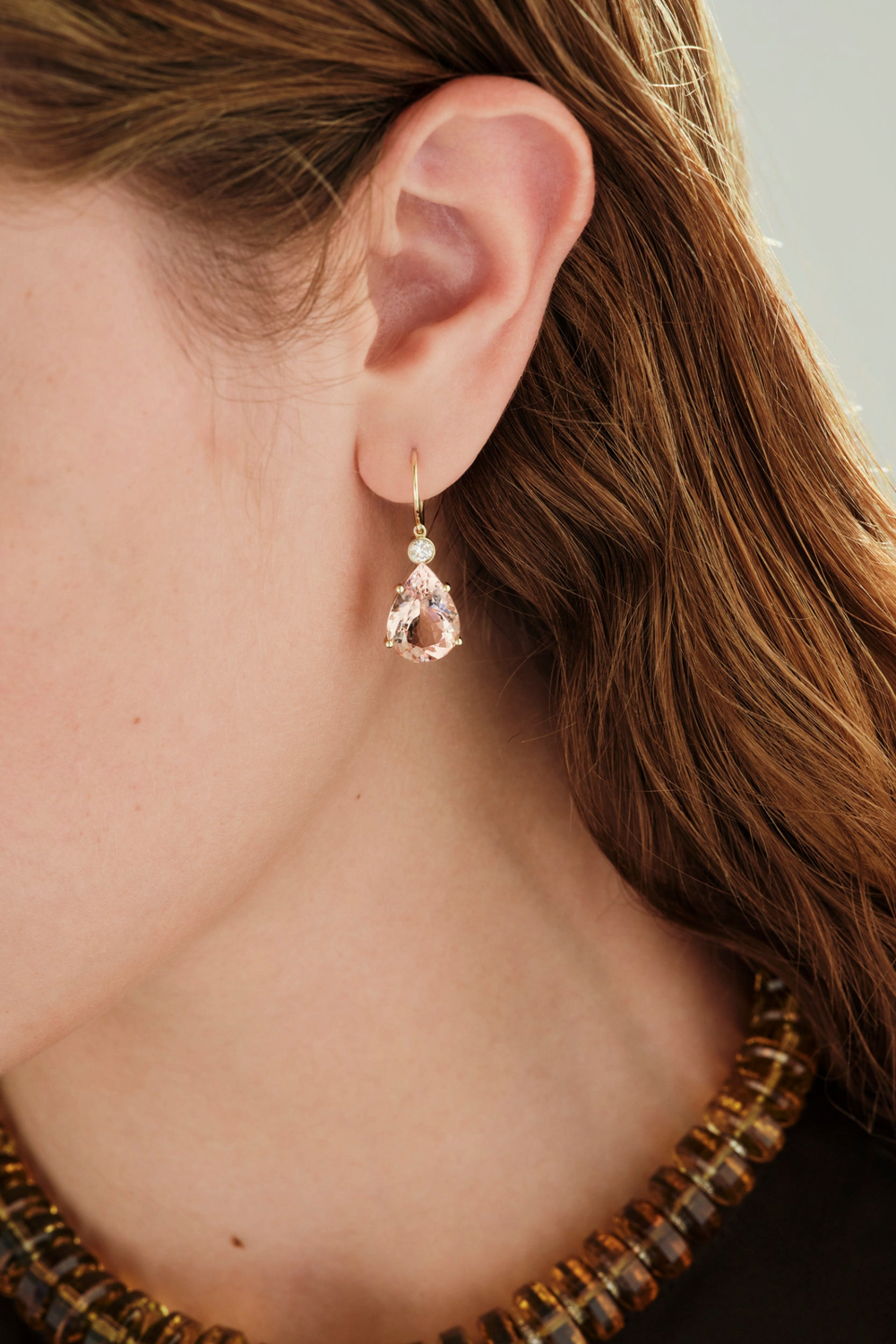 Ileana Makri pear-cut morganite drop earrings in 14k yellow gold with a single diamond accent worn on a model