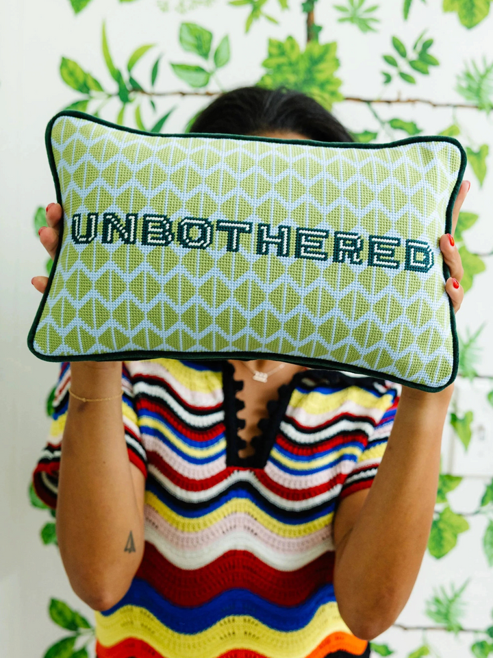 Ileana Makri Unbothered needlepoint pillow with green geometric pattern and velvet backing held by a person