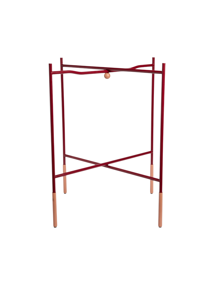 Ileana Makri foldable tray stand in a deep Bordeaux red finish with sturdy metal construction and light wood accents.