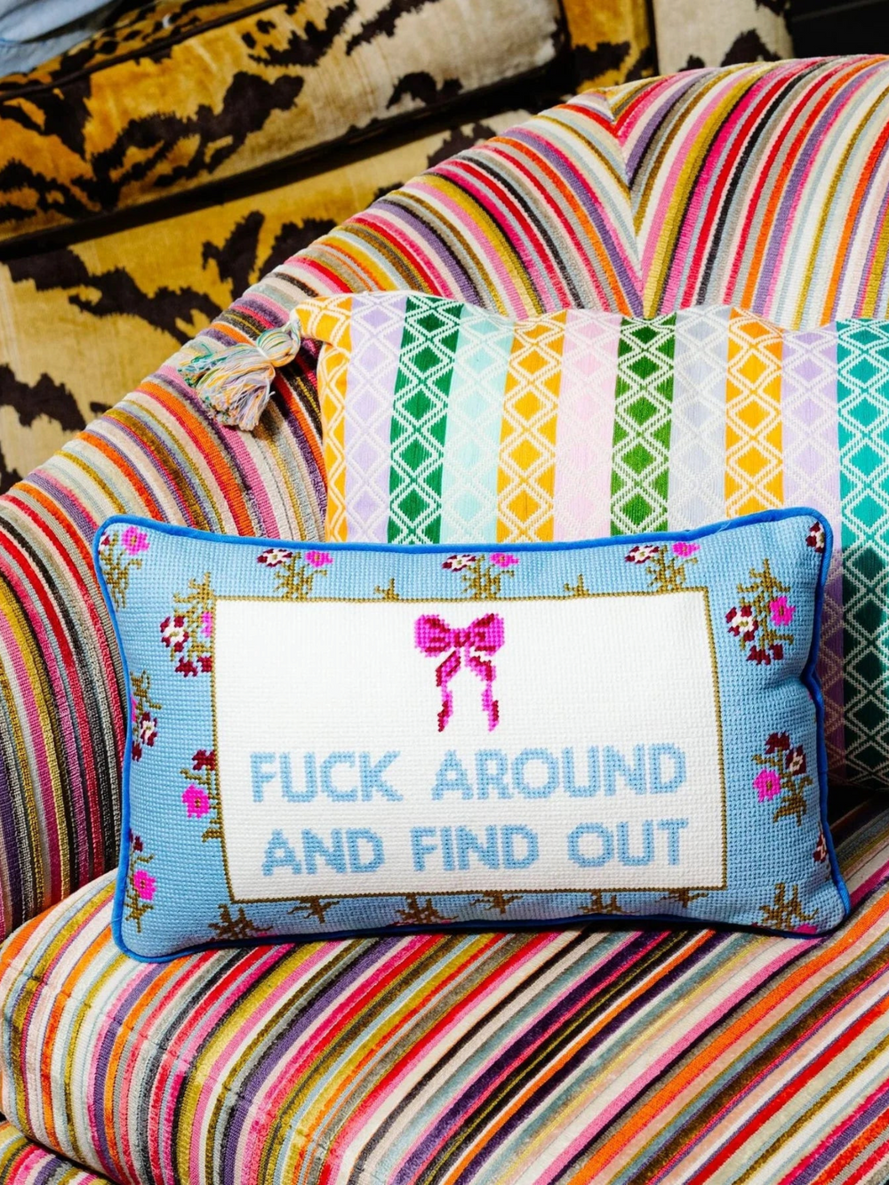 Ileana Makri needlepoint pillow with blue background, pink bow, and the phrase F*** Around And Find Out