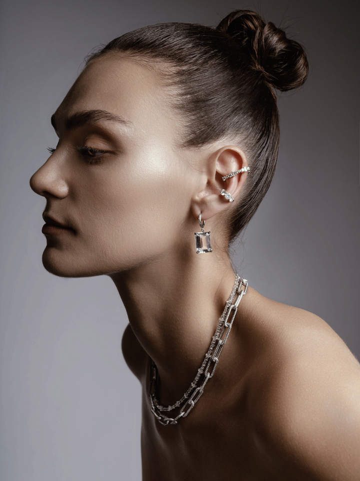 Ileana Makri Royal Crown white gold hoop earrings with white topaz and diamonds worn by a model in profile view.
