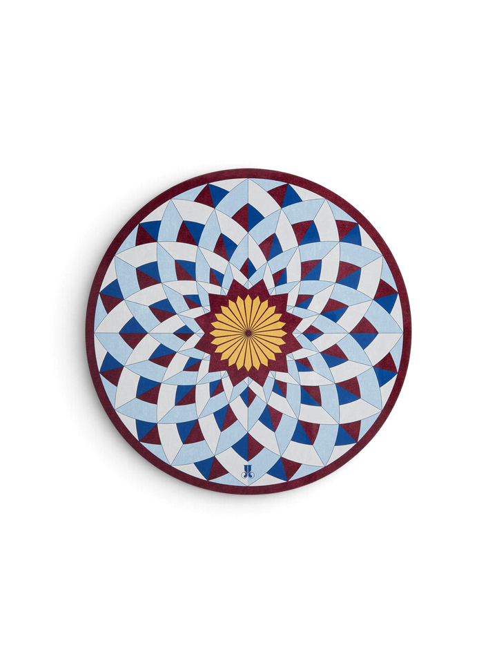 Ileana Makri Lotus of Life circular placemat with blue, white, and burgundy geometric mosaic pattern and cork backing.
