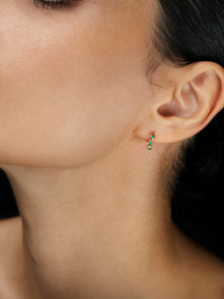 Ileana Makri Stepping Stone hoop earring in 18k yellow gold featuring emeralds worn on a model ear