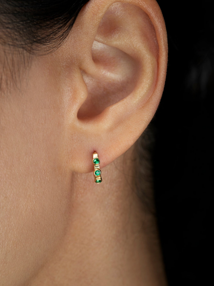 Ileana Makri Stepping Stone hoop earring in 18k yellow gold featuring emeralds worn on a pierced earlobe
