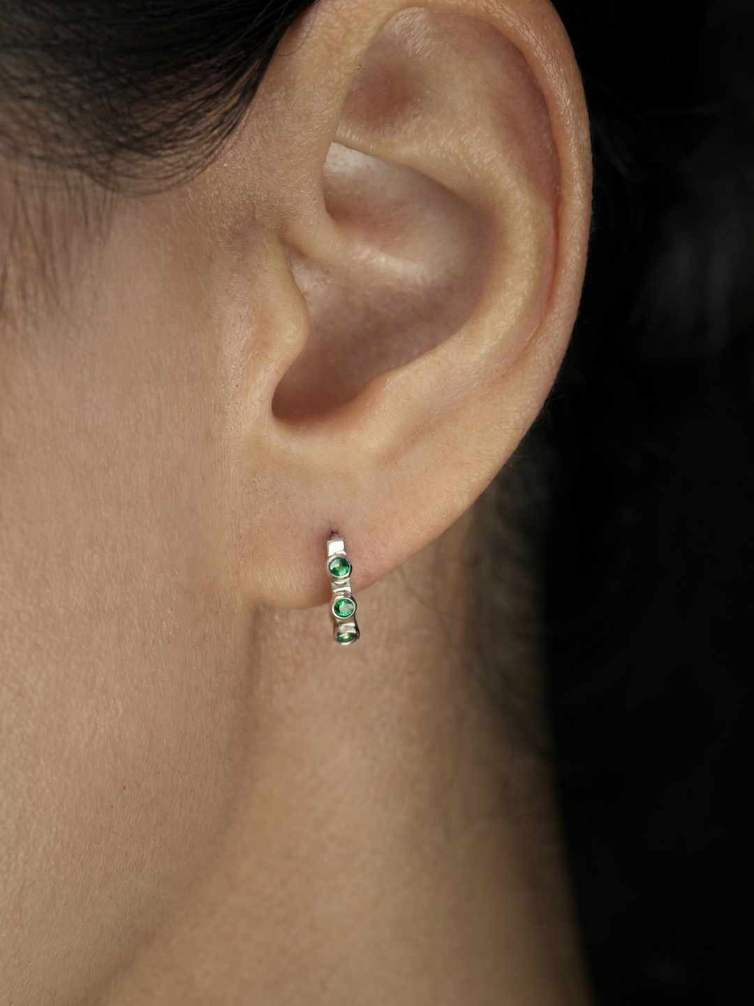 Ileana Makri Stepping Stone hoop earring in 18k white gold featuring three bezel-set emeralds worn on a pierced ear.