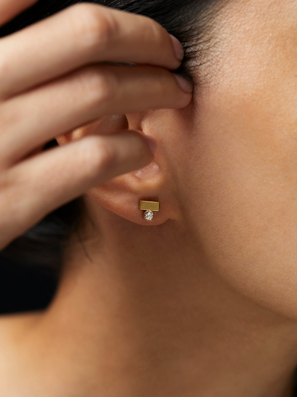 Ileana Makri Stepping Stone stud earring in 18k yellow gold with a white diamond worn on an earlobe