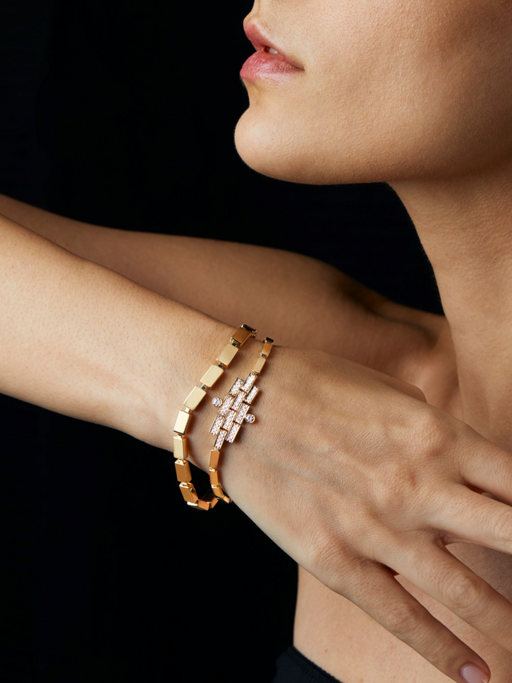 Ileana Makri 18k yellow gold waterfall bracelet with linear sculptural design worn on a model against black background
