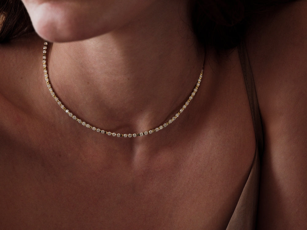 Close-up of a person wearing a delicate gold necklace with diamonds
