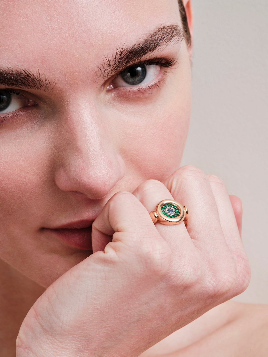 Ileana Makri Round Eye ring in 18k white gold with tsavorite, white diamonds, and blue sapphires on a model's hand.