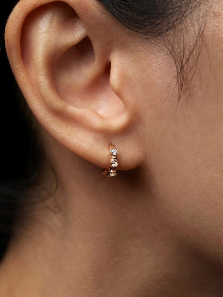 Ileana Makri Stepping Stone midi hoop earring in 18k rose gold featuring pavé white diamonds and rubies on an earlobe.