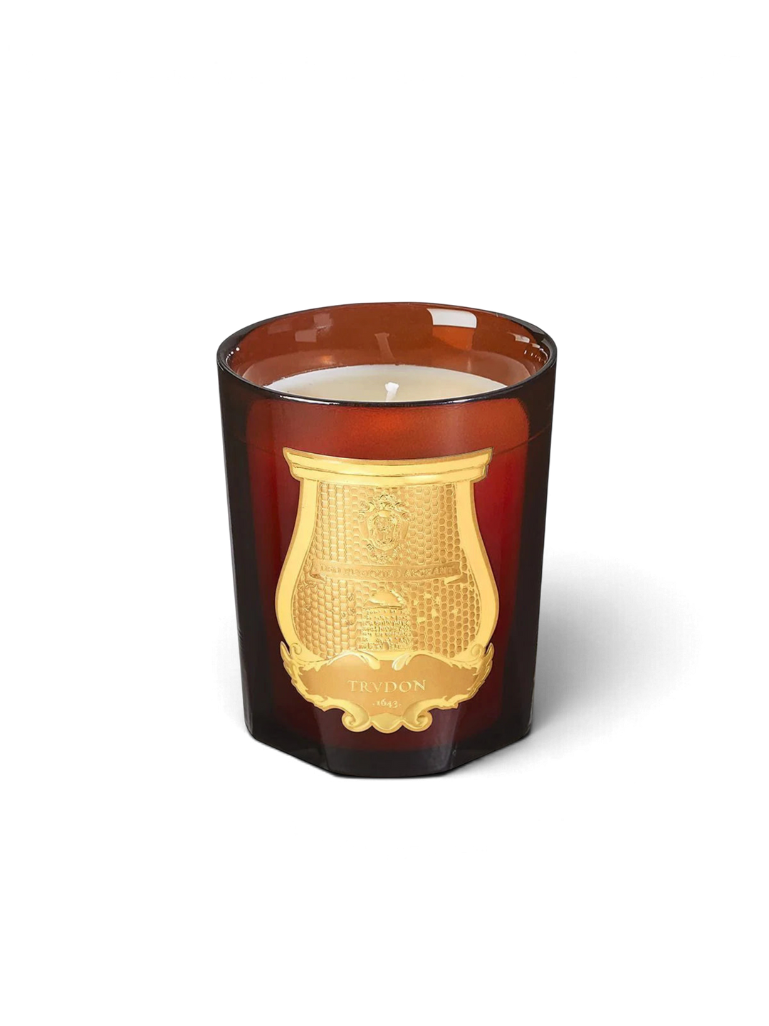 Ileana Makri Trudon Cire beeswax candle in an amber glass vessel with a gold embossed crest label