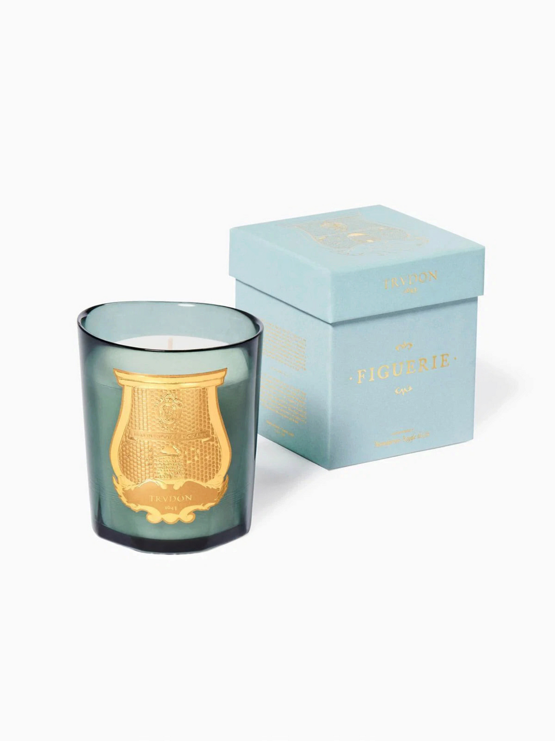 Ileana Makri Figuerie Royal Fig candle in a green glass vessel with gold emblem next to its light blue gift box.