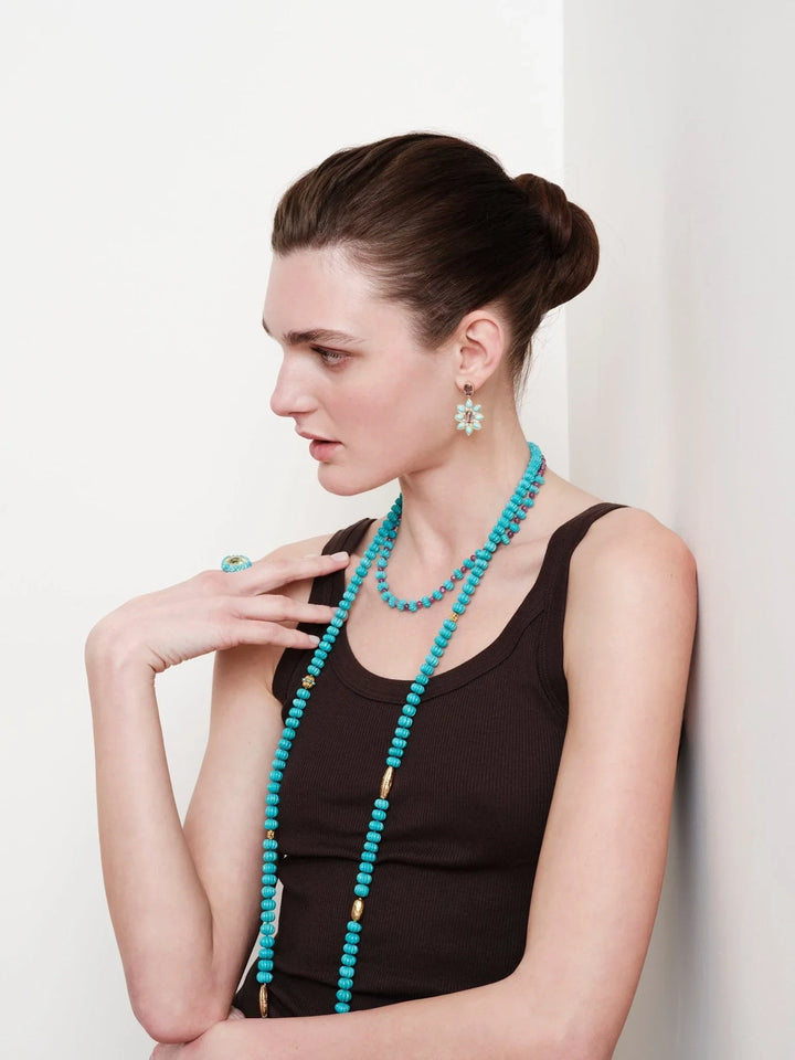 Woman wearing turquoise beaded necklace, turquoise flower earrings, and matching ring